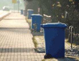 view down street of garbage recycling cans at the curb