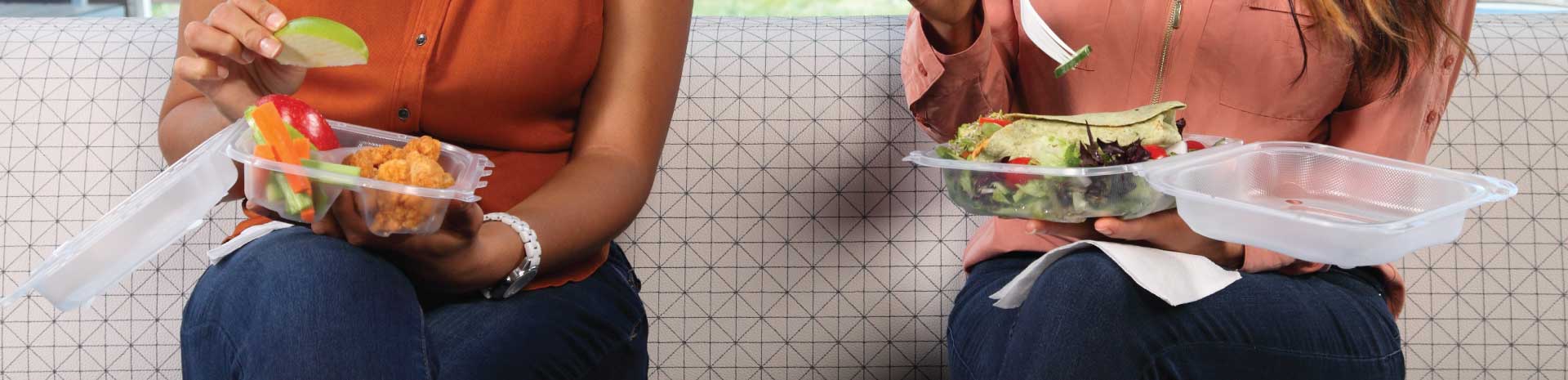 2 women eating from clear hinged food containers